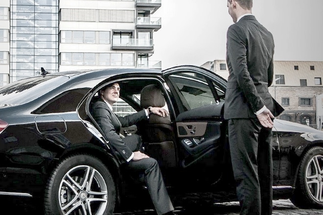 Chauffeur holding the door of a Mercedes for a passenger